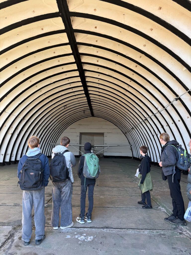 Schüler stehen in einer leeren Flugzeughalle.