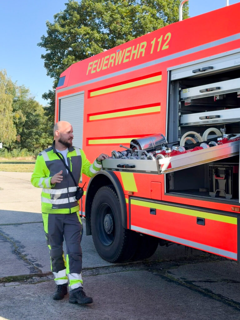 Ein Feuerwehrmann steht neben einem geöffneten Löschfahrzeug.